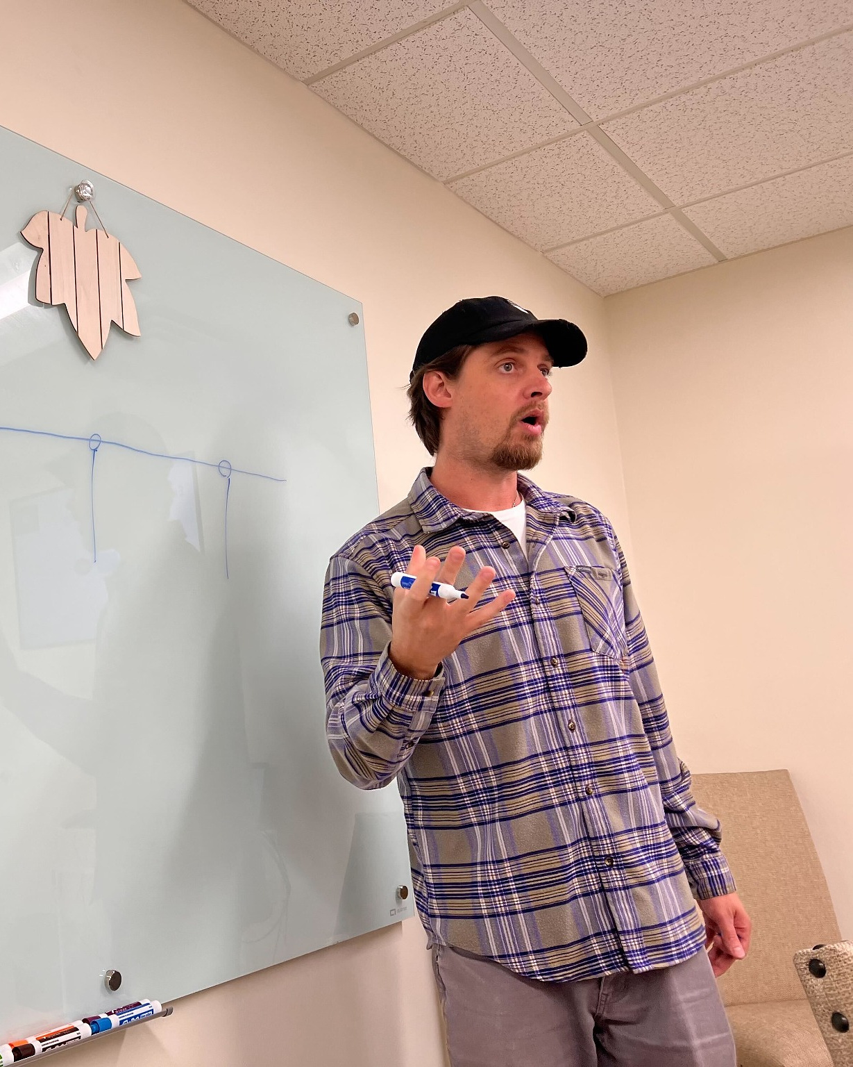 Jack Vertovec facilitates a collaborative discussion beside a glass board.