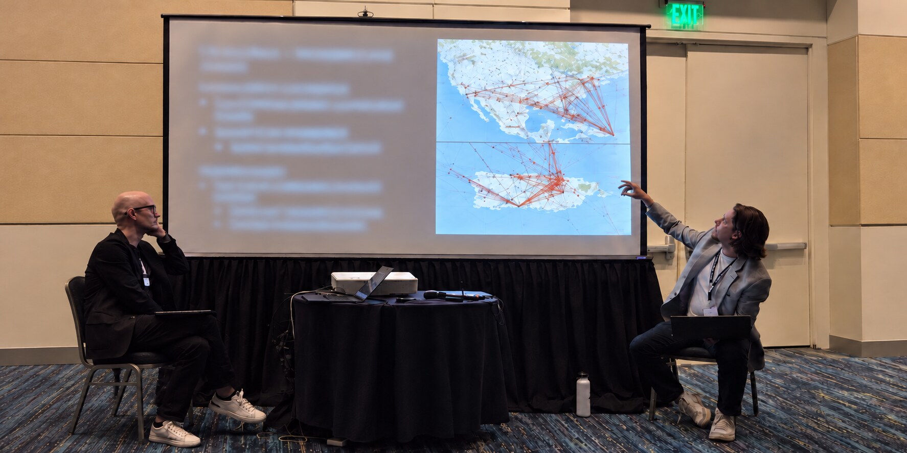 Jack Vertovec presents physician migration research during a professional conference session while a colleague listens.